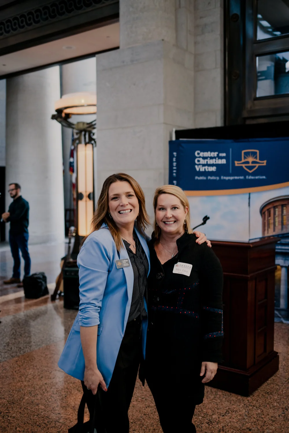 Two attendees, in front of the CCV banner